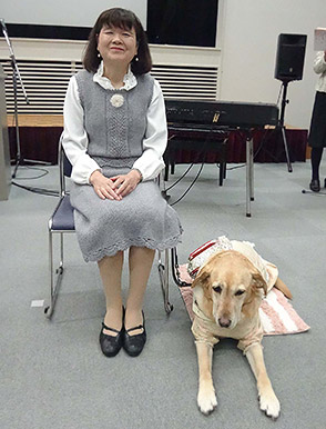 中村さんの傍に座る盲導犬コニーの写真