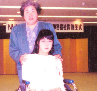 障害福祉賞　贈呈式会場で、お母様と一緒に映る林さんの写真
