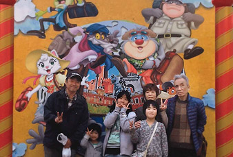 キャラクターの看板の前で藤野さんと息子さんの家族の記念写真