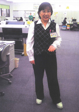 オフィス内で制服の森川さんが立っている写真