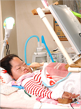 写真：自宅のベッドで過ごす平本さん。枕元に呼吸器が置いてある 