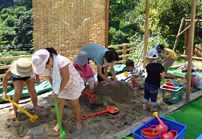 写真：砂場用の遊具で遊ぶ子どもと親
